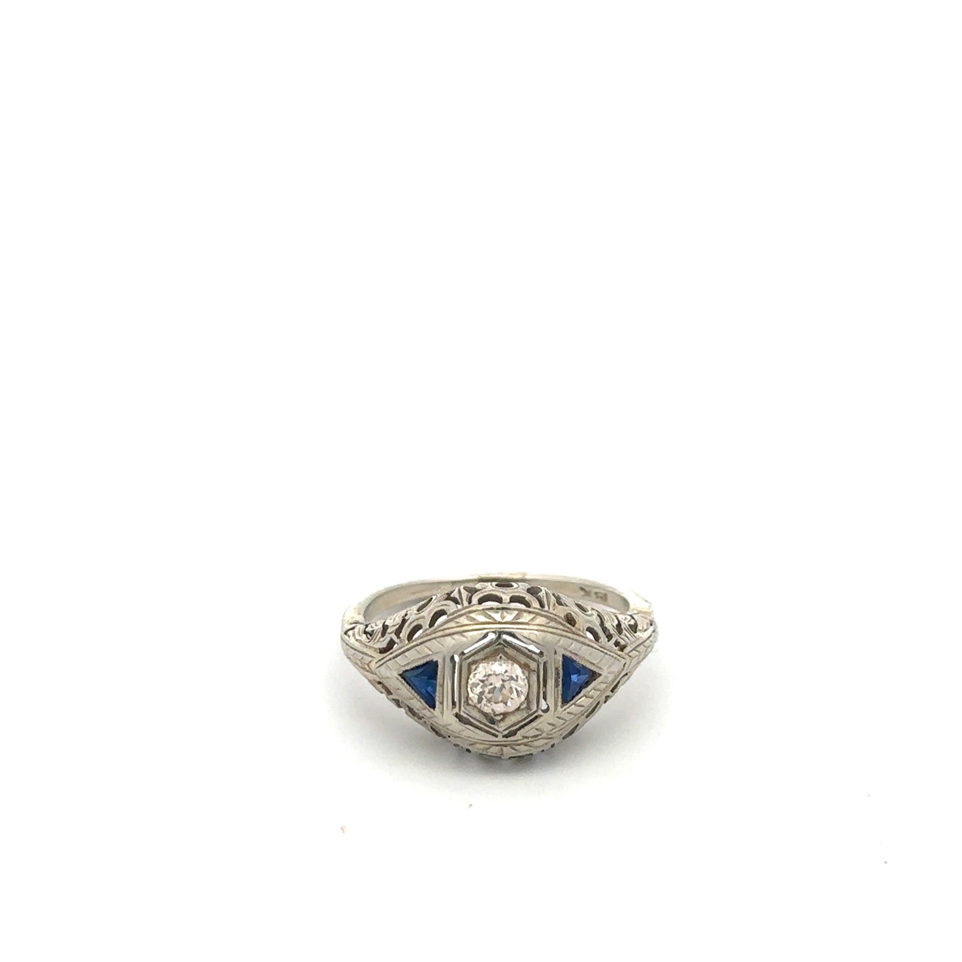 Art deco sapphire and diamond ring in 18k white gold featuring intricate vintage design and sparkling gemstones.